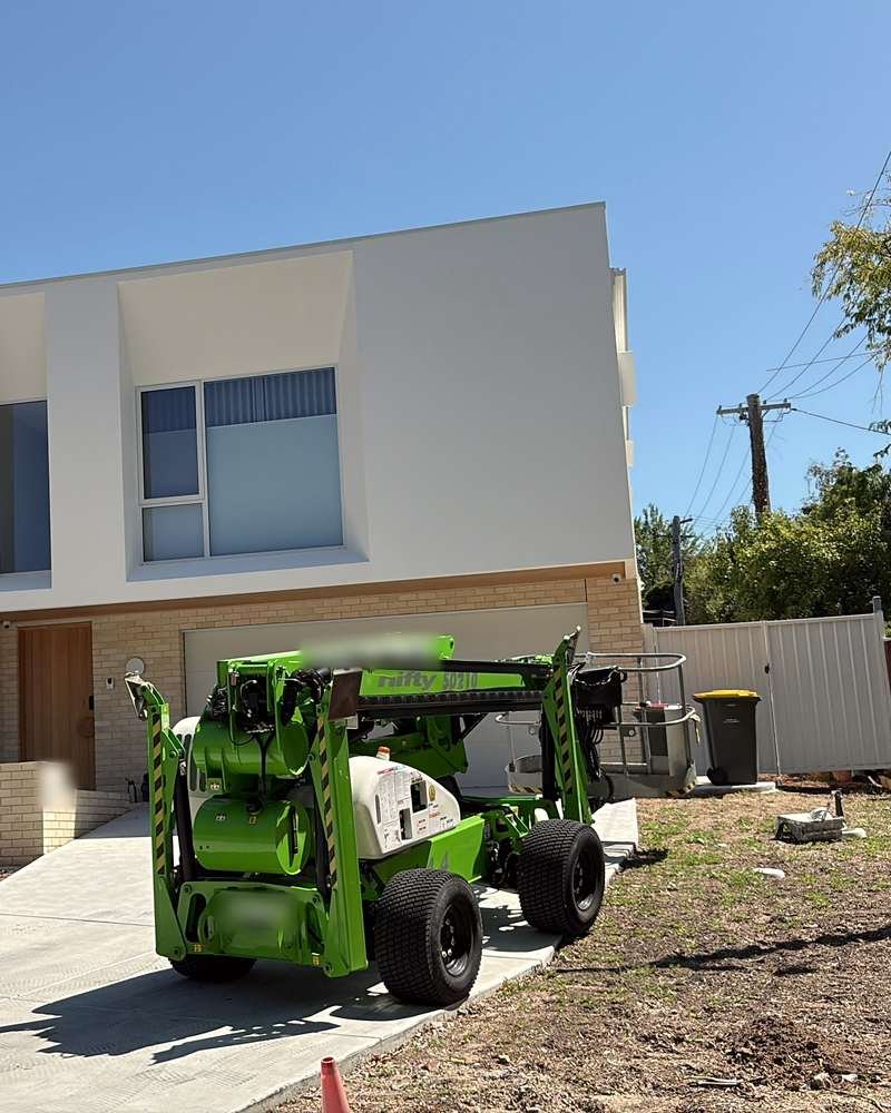 Boom lift set up in front of a two-storey new build for high exterior work