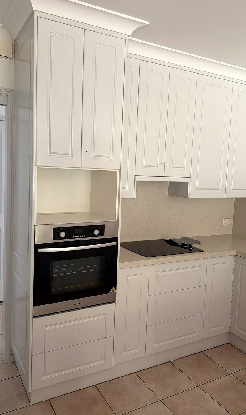 Kitchen with white-painted raised-panel cabinetry, a built-in oven and a cooktop